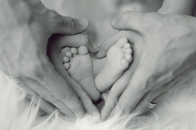 newborn's feet, parents hands forming a heart