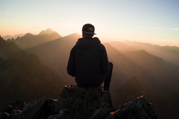 mand sidder på et bjerg til solnedgangen