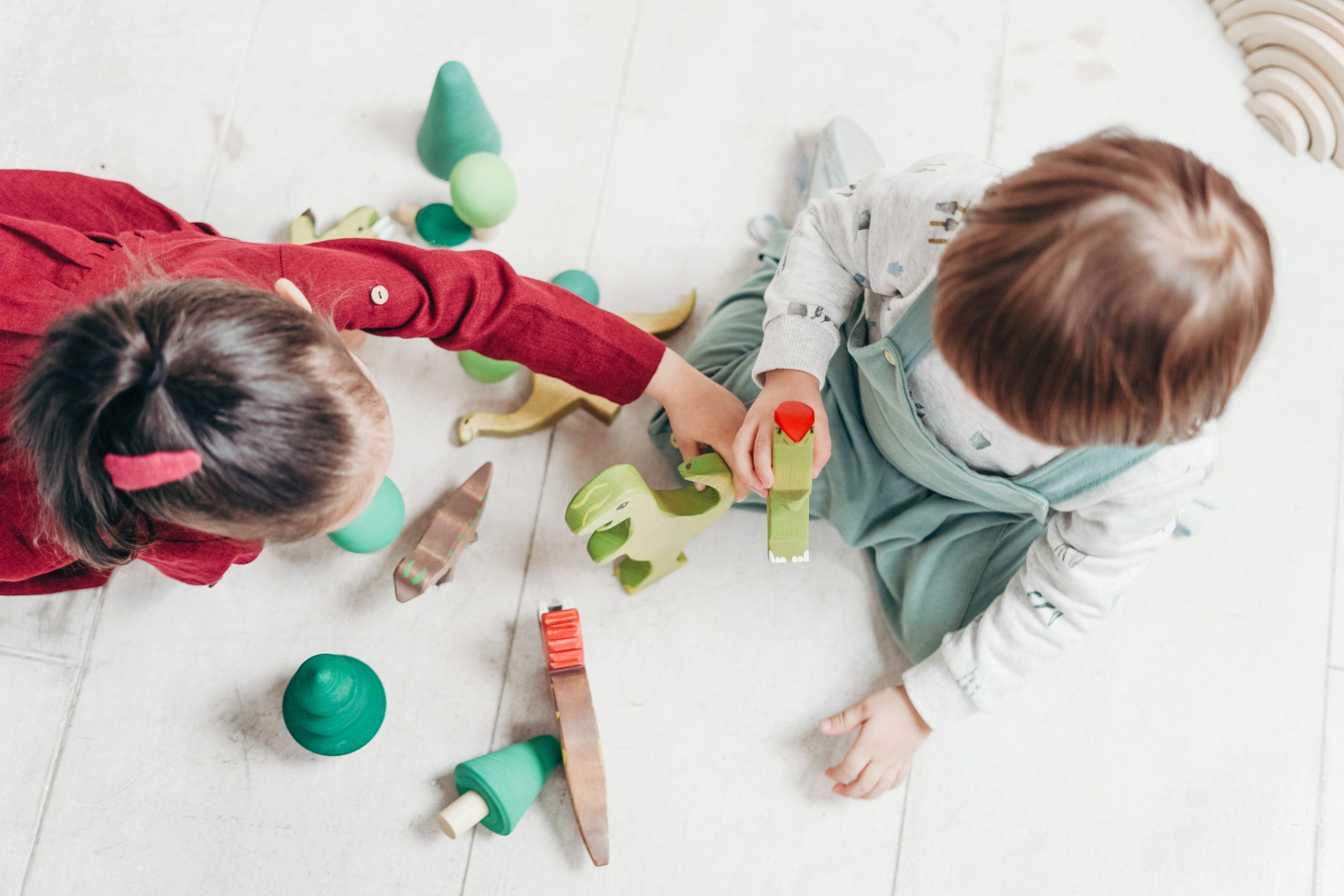 To børn der sidder og leger med legetøj set oppefra